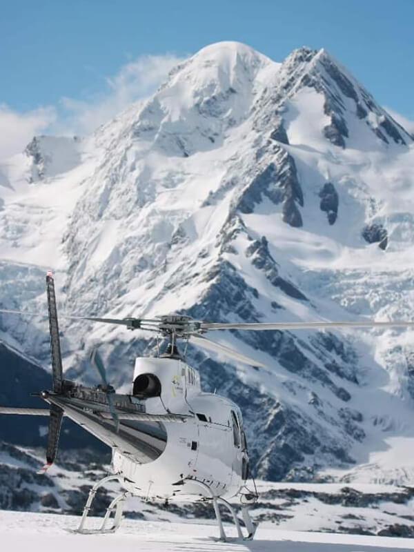 helicopter on snow in front of mountain range