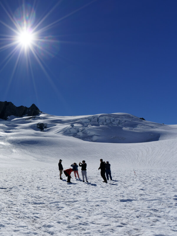 people standing on snow with mountains in background