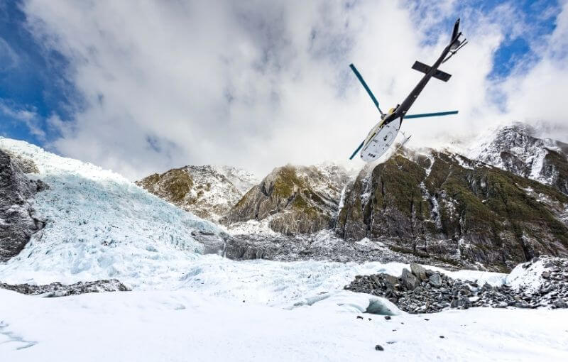 Helicopter flying over snow and glacier