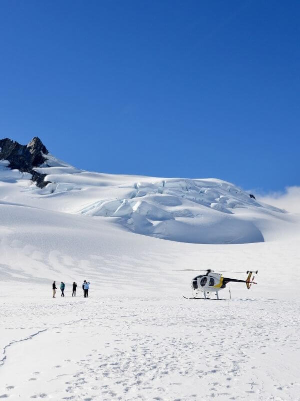 Helicopter landing on snow with passengers walking on snow