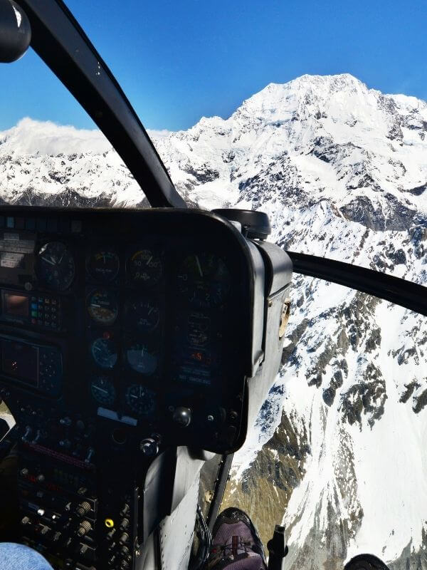 cockpit of helicopter overlooking snowy mountains