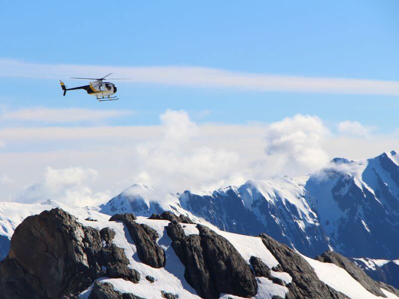 cockpit of helicopter overlooking snowy mountains